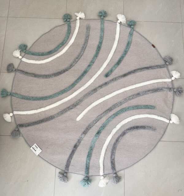 tapis rond pour enfant couleur gris , avec des méches en relief et des pompons